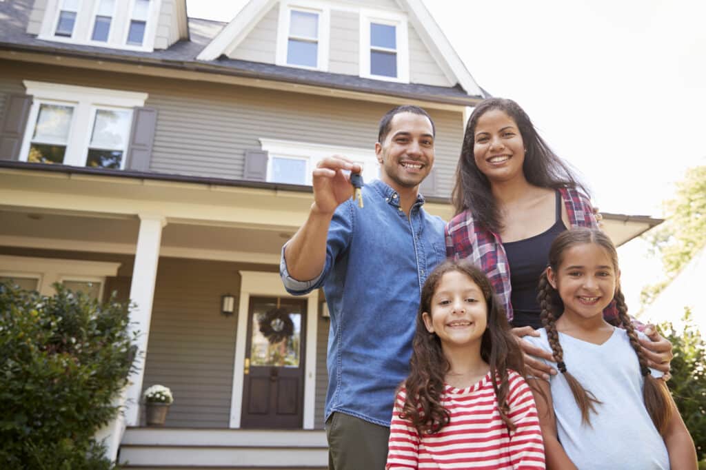 Portrait Of Family Holding Keys To New Home On Moving In Day