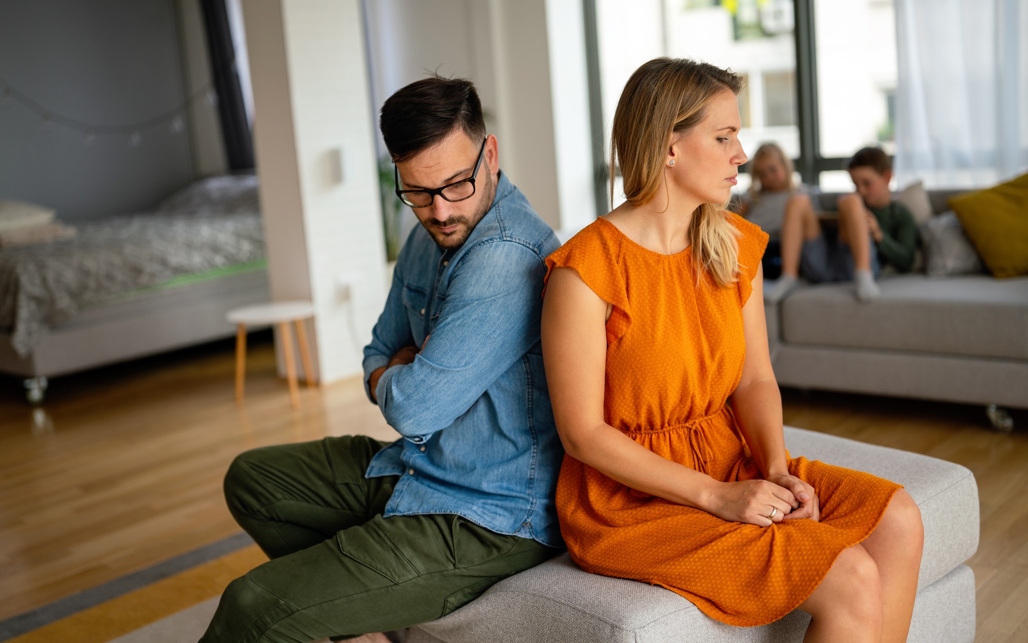 Sad pensive couple thinking of relationships problems sitting on sofa, conflicts in marriage, upset couple after fight dispute, making decision of breaking up get divorced